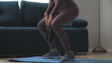 slender-legs-of-sportswoman-training-at-home-doing-squats-with-weight-in-hands-wellness-and-losing-weight-fitness-at-weekend-sporty-and-healthy-lifestyle-details-of-body-parts